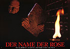 Jorge mit einem verbotenen Buch in der Hand in der Bibliothek, vorne rechts bereits eine Flamme